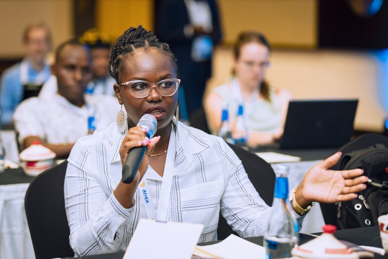 A woman in glasses speaking into a microphone